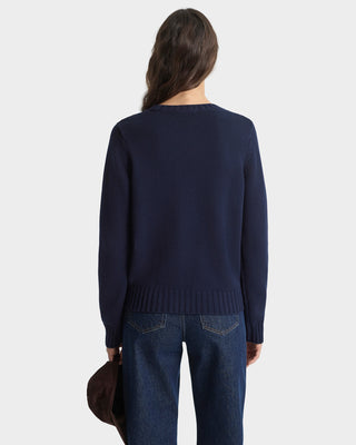 Person wearing a navy sweater and blue jeans on a white background