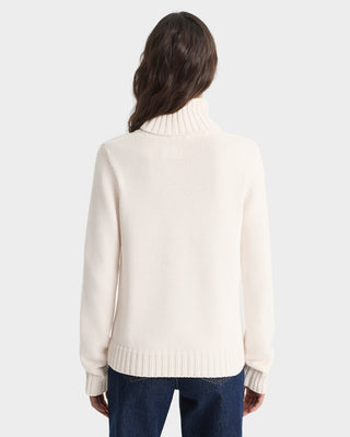 Person wearing a cream sweater on a white background