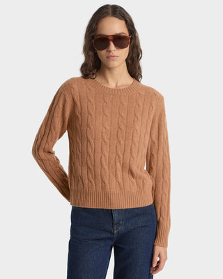 Woman wearing a brown cable knit sweater and sunglasses on a white background
