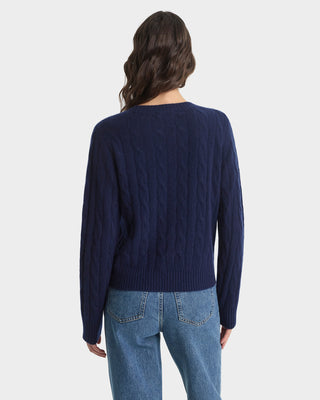 Person wearing a navy sweater and blue jeans on a white background