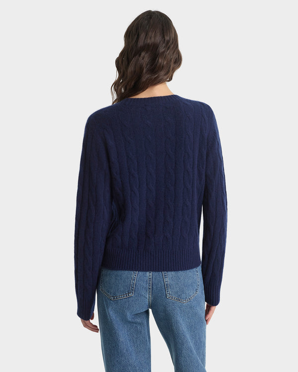 Person wearing a navy sweater and blue jeans on a white background