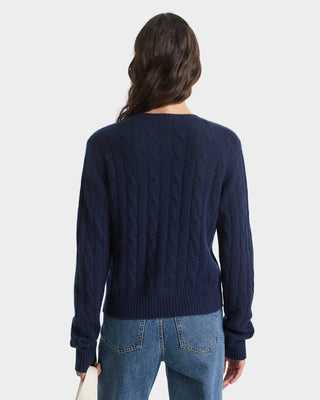 Person wearing a navy sweater and blue jeans on a white background