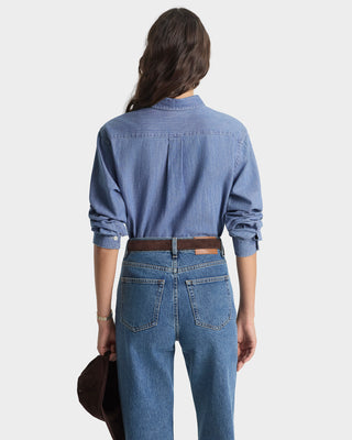 Person wearing a blue denim shirt and jeans on a white background