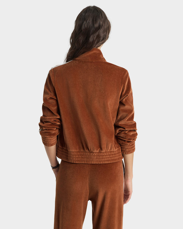 Person wearing a brown velvet tracksuit on a white background