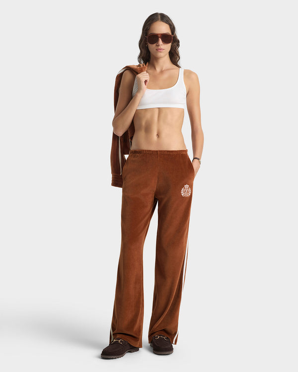 Woman wearing brown pants with a logo and a white top on a white background