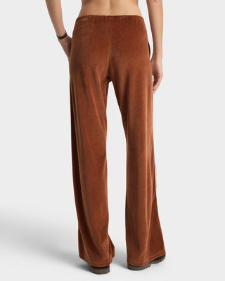 Brown velvet pants worn by a person on a white background