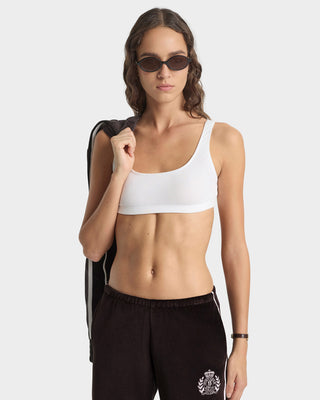 Woman wearing a white sports bra and black pants on a white background