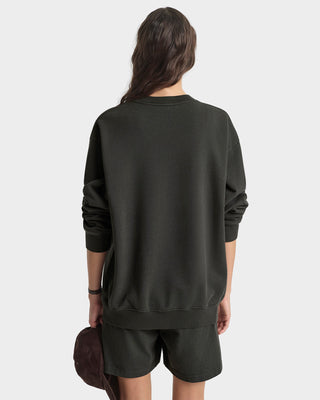 Person wearing a dark green sweatshirt and shorts set on a white background