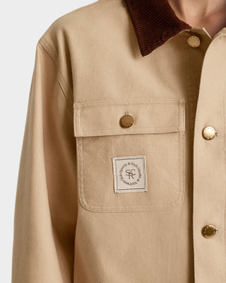 Beige jacket with brown collar and visible brand label on a light gray background
