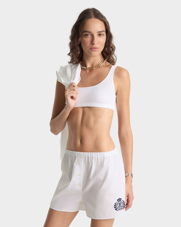 Woman wearing a white sports bra and shorts on a plain background