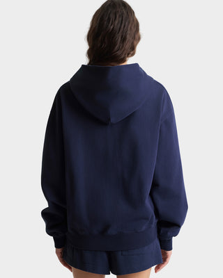 Person wearing a navy blue hoodie and shorts on a white background