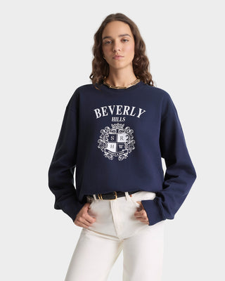 Person wearing a navy blue sweatshirt with 'Beverly Hills' print on a white background