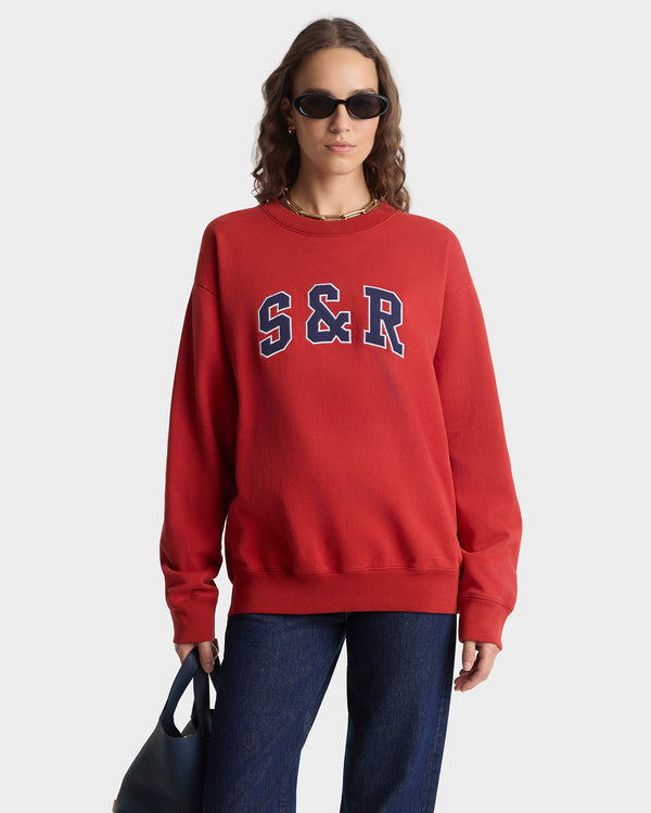Person wearing a red sweatshirt with 'S & R' on a white background