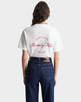 Person wearing a white t-shirt with red text and blue jeans on a white background
