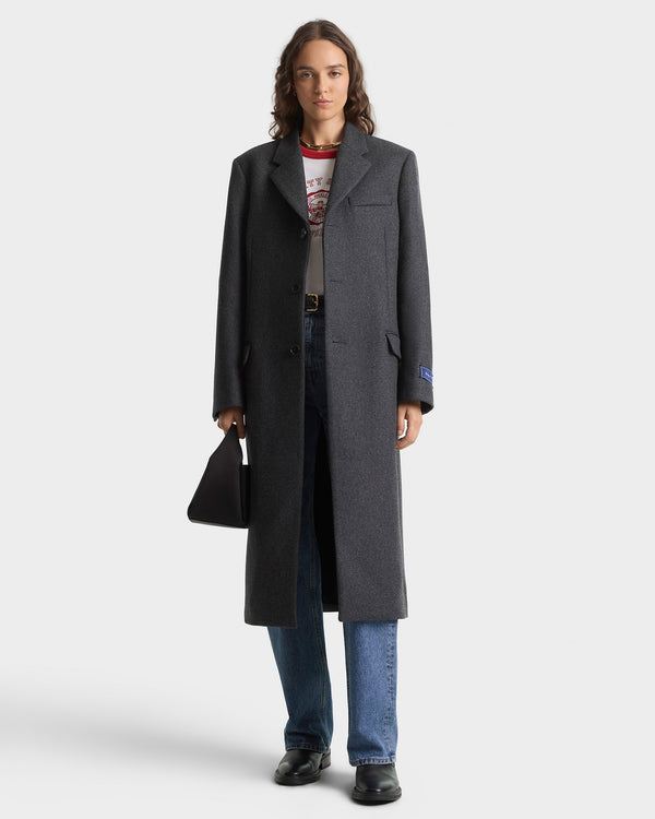 Person wearing a long dark coat on a white background
