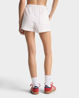 Person wearing white shorts and red sneakers on a plain background