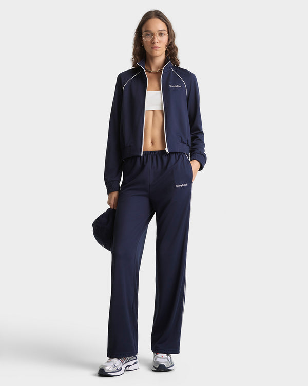Woman wearing a navy tracksuit with a white background
