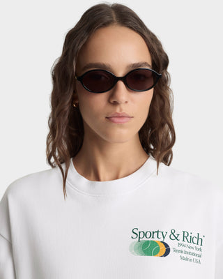 Person wearing a white sweatshirt with Sporty & Rich logo on a light gray background