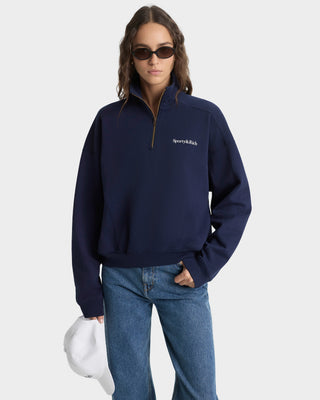 Person wearing a navy blue sweater with a brand logo on a white background