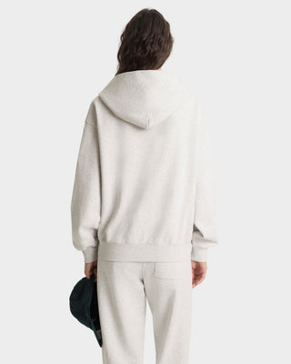 Person wearing a light gray hoodie and pants on a white background