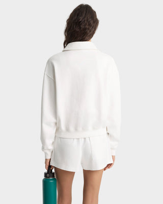 Person wearing a white outfit holding a teal water bottle on a plain background