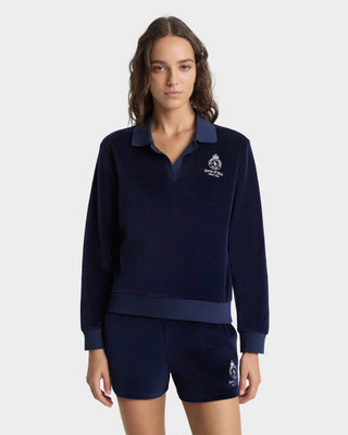 Woman wearing a navy blue tracksuit with a logo on a white background