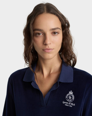Woman wearing a navy blue polo shirt with a logo on a white background