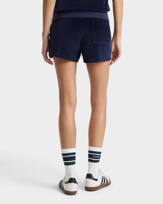 Person wearing navy shorts and white socks with green stripes on a white background