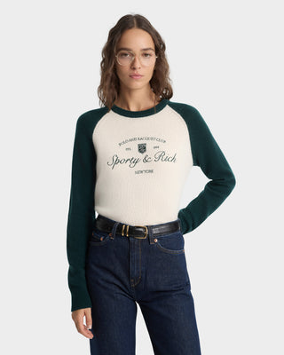 Woman wearing a green and beige long-sleeve shirt with text, standing against a white background