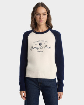 Woman wearing a navy and white sweater with 'Sporty & Rich' branding on a white background