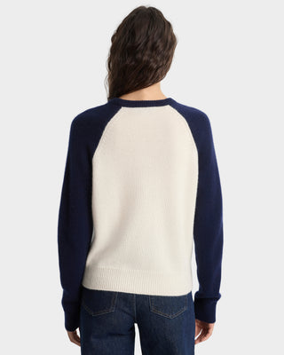 Person wearing a navy and cream baseball sweater on a white background