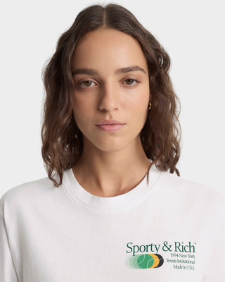 Woman wearing a white sweatshirt with Sporty & Rich logo on a light gray background