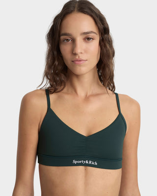Woman wearing a green sports bra with 'Sporty&Rich' branding on a white background