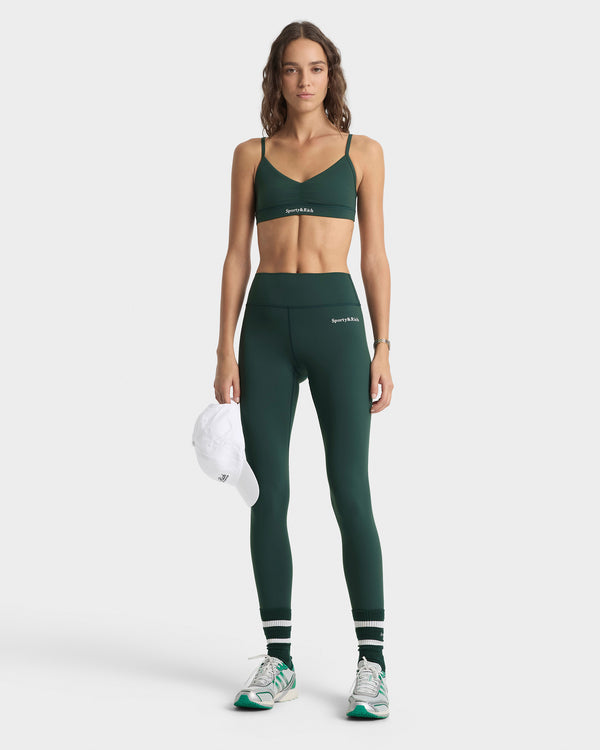 Woman wearing a green sports bra and leggings set on a white background
