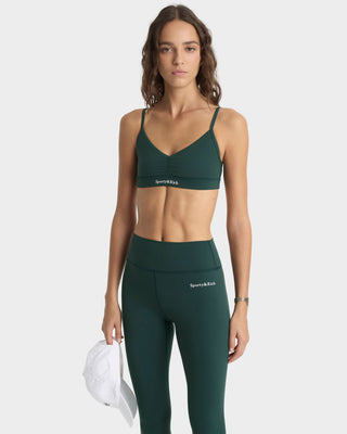 Woman wearing a green sports bra and leggings set on a white background