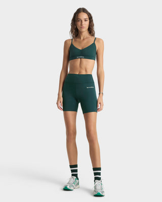 Woman wearing a green sports bra and shorts set on a white background