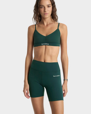 Woman wearing a green sports bra and shorts set on a white background