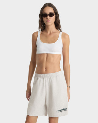 Woman wearing a white sports bra and beige shorts on a white background
