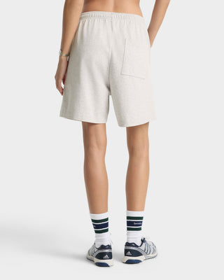 Person wearing light-colored shorts and Adidas shoes on a white background
