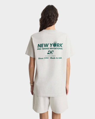 Person wearing a gray t-shirt with 'New York Pro Tennis Invitational' text on the back.