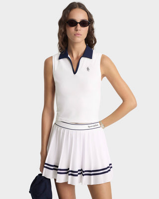 Woman wearing a white tennis dress with navy accents on a white background