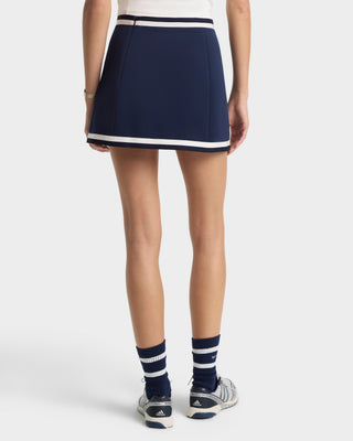 Person wearing a navy skirt with white trim on a white background