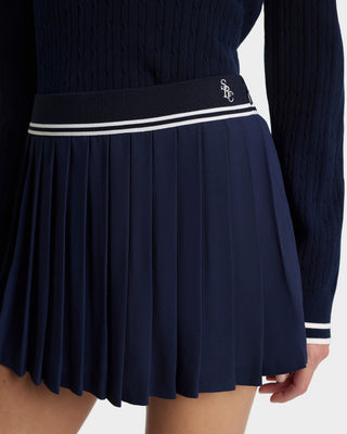 Navy pleated skirt with white and black band on a white background