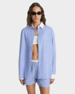 Woman wearing a light blue striped shirt and shorts set on a white background