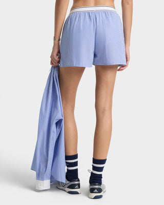 Person wearing light blue shorts and navy socks with white stripes, holding a matching shirt.