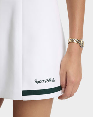 White skirt with green trim and 'Sporty&Rich' branding, worn by a person.