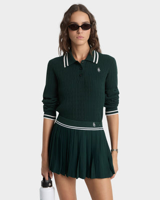 Woman wearing a green ribbed sweater and skirt set with a brand logo on a white background