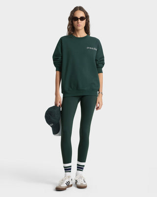 Person wearing a green sweatshirt and leggings set on a white background