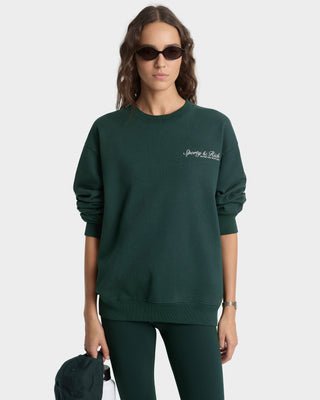Woman wearing a green sweatshirt with a brand logo on a white background