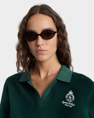Woman wearing a green polo shirt with a logo on a white background